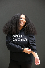 Woman wearing black hoodie with 'Anti-Racist' in white lettering.