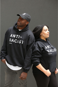 Man and Woman wearing black hoodies with 'Anti-Racist' in white lettering.