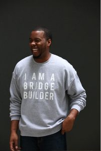 Man wearing gray sweatshirt with 'I Am A Bridge Builder' in white lettering.